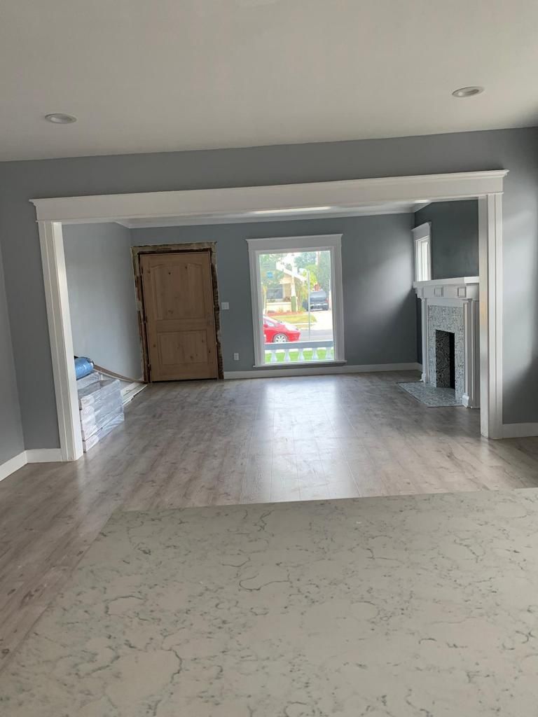 An empty living room with hardwood floors and a fireplace.