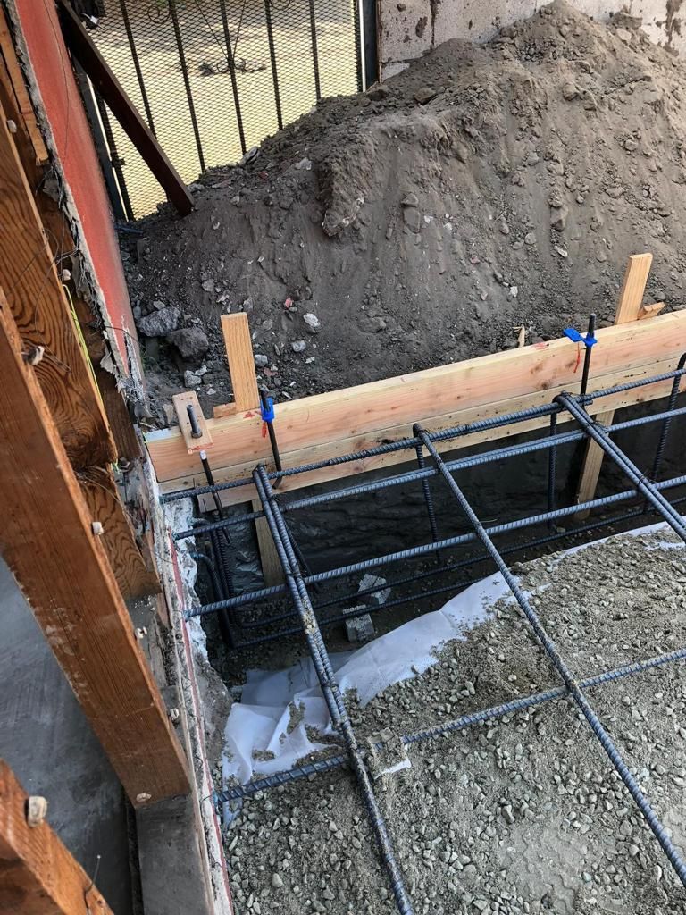 A concrete foundation is being built next to a brick wall.