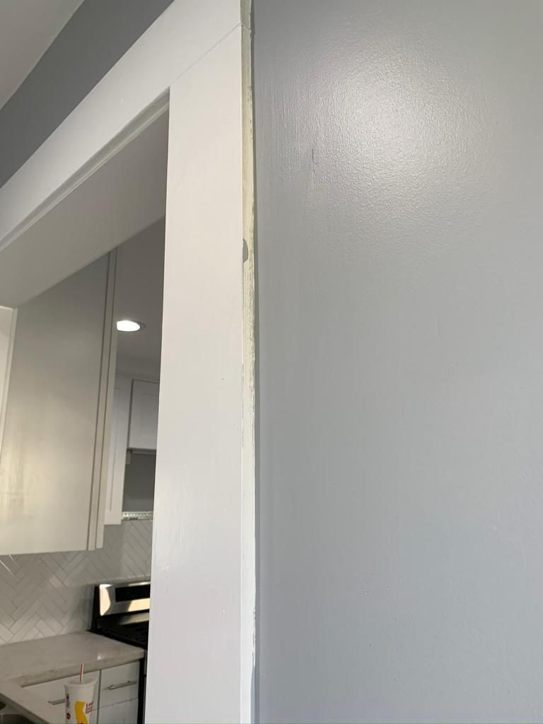 A kitchen with white cabinets and a gray wall.
