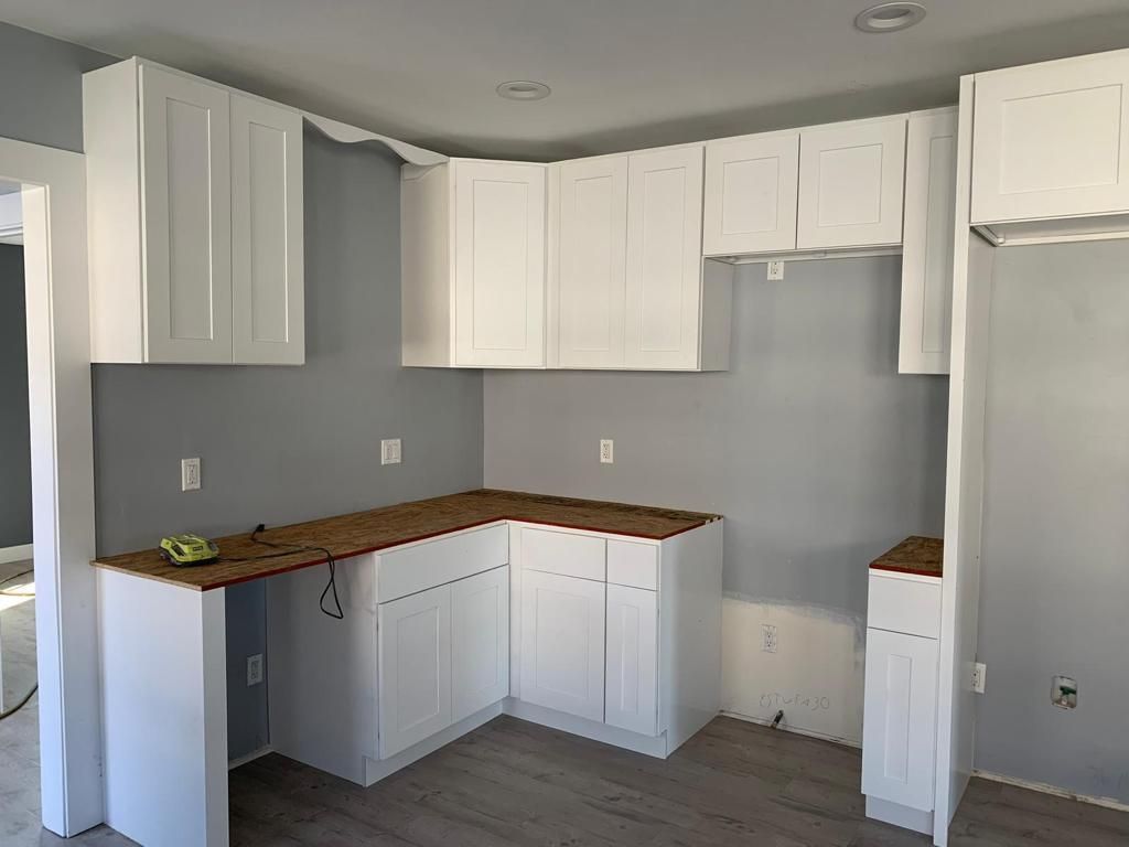 A kitchen with white cabinets and a wooden counter top.
