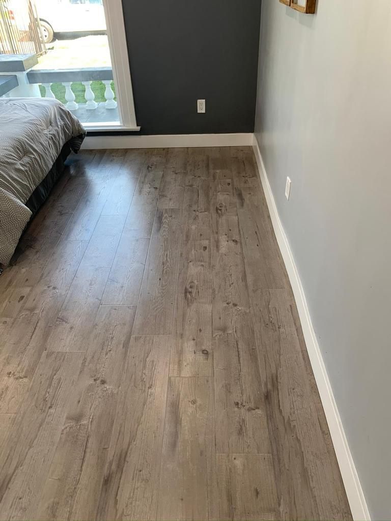A bedroom with hardwood floors and a bed.