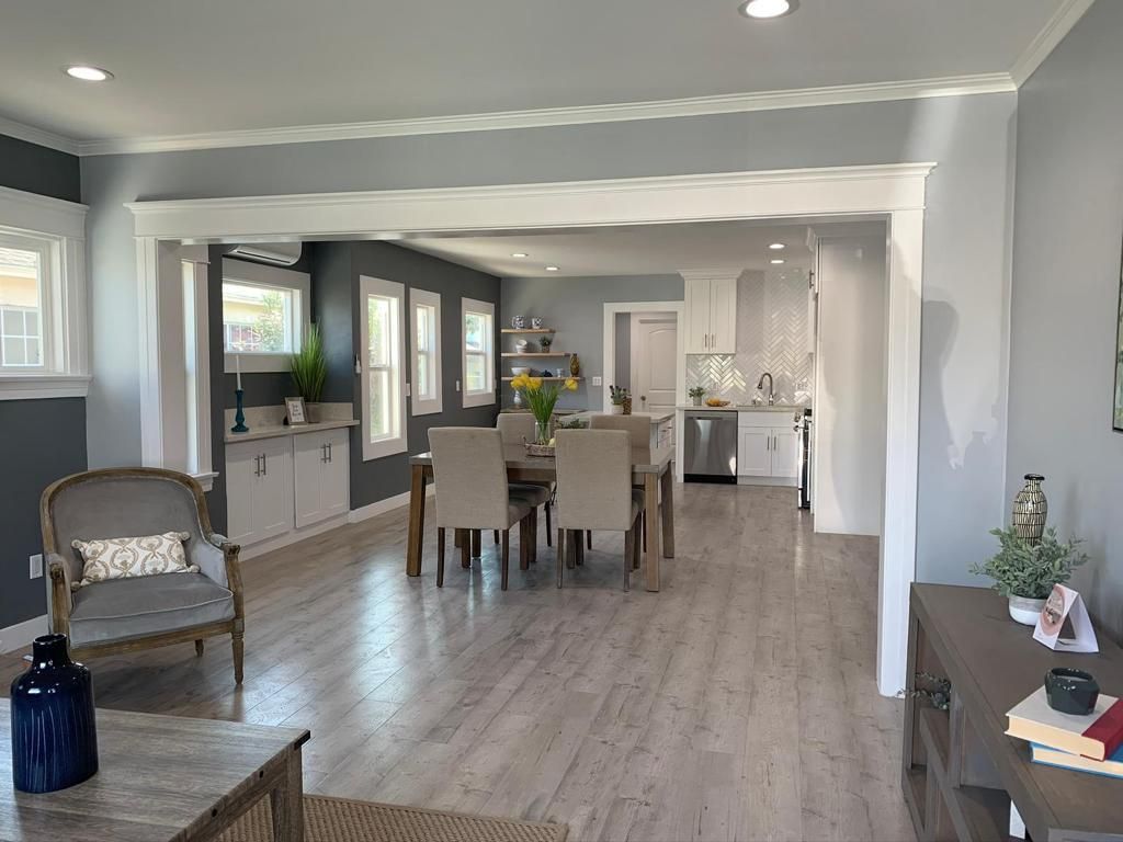 A living room with a dining room table and chairs and a kitchen.