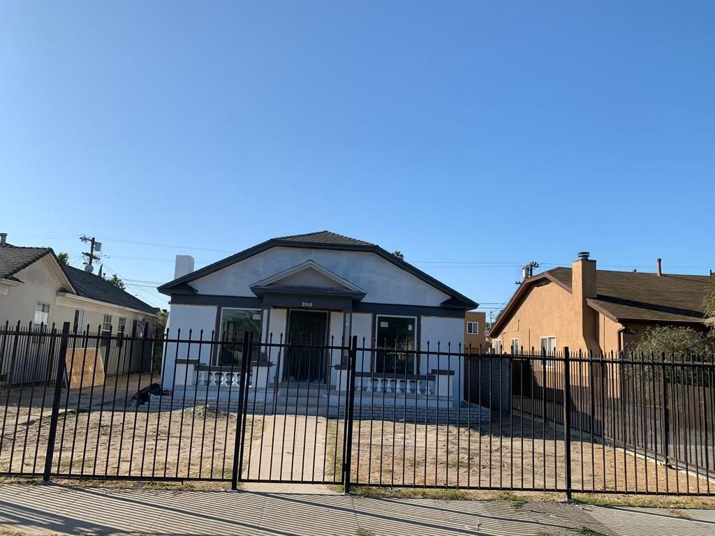 A house with a fence around it and a blue sky in the background.