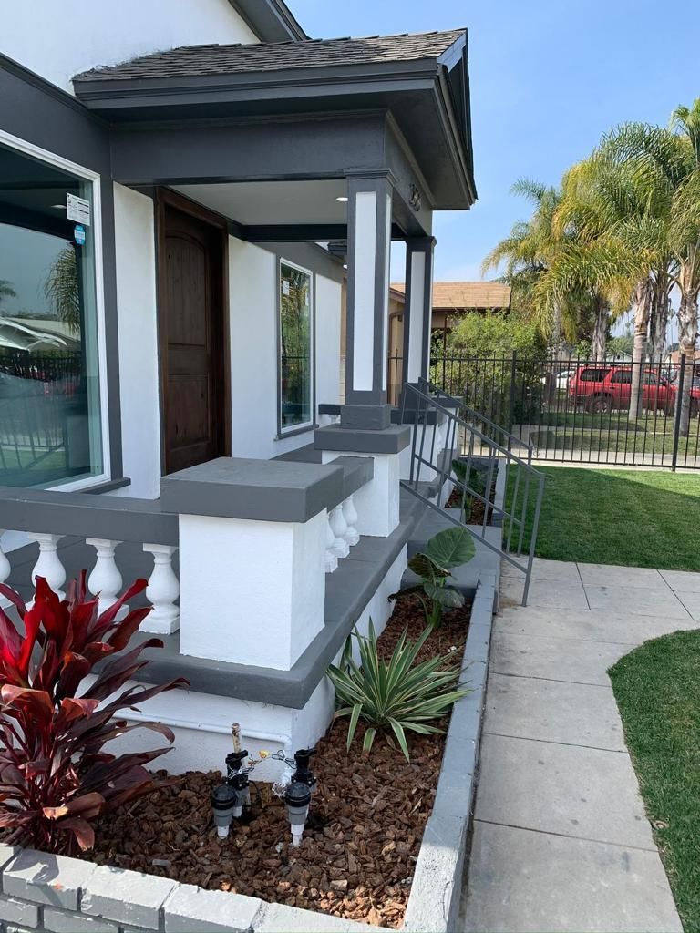 A white house with a porch and stairs in front of it.