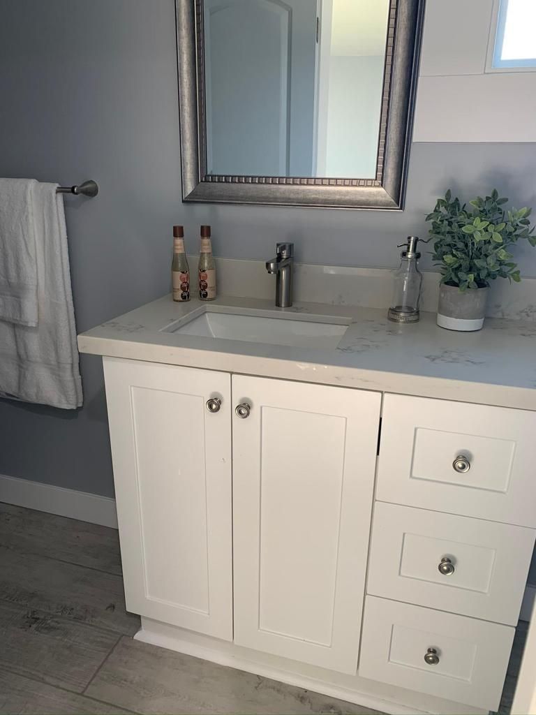 A bathroom with a sink , mirror and towel rack.