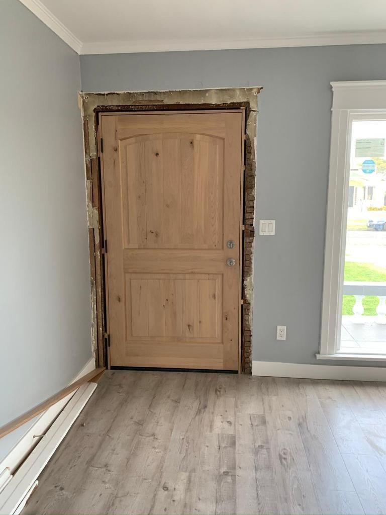 An empty room with a wooden door and a window.