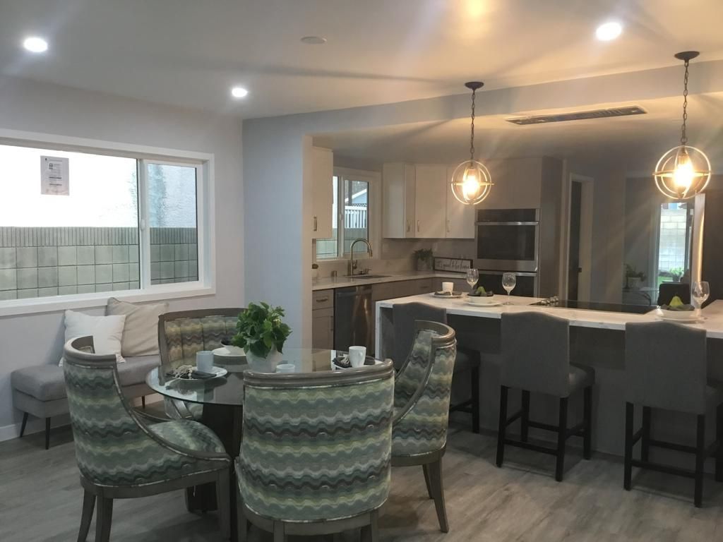 A dining room with a table and chairs and a kitchen in the background.
