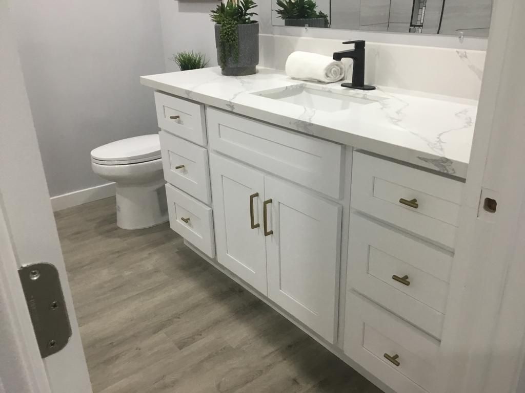 A bathroom with a toilet , sink , and cabinets.