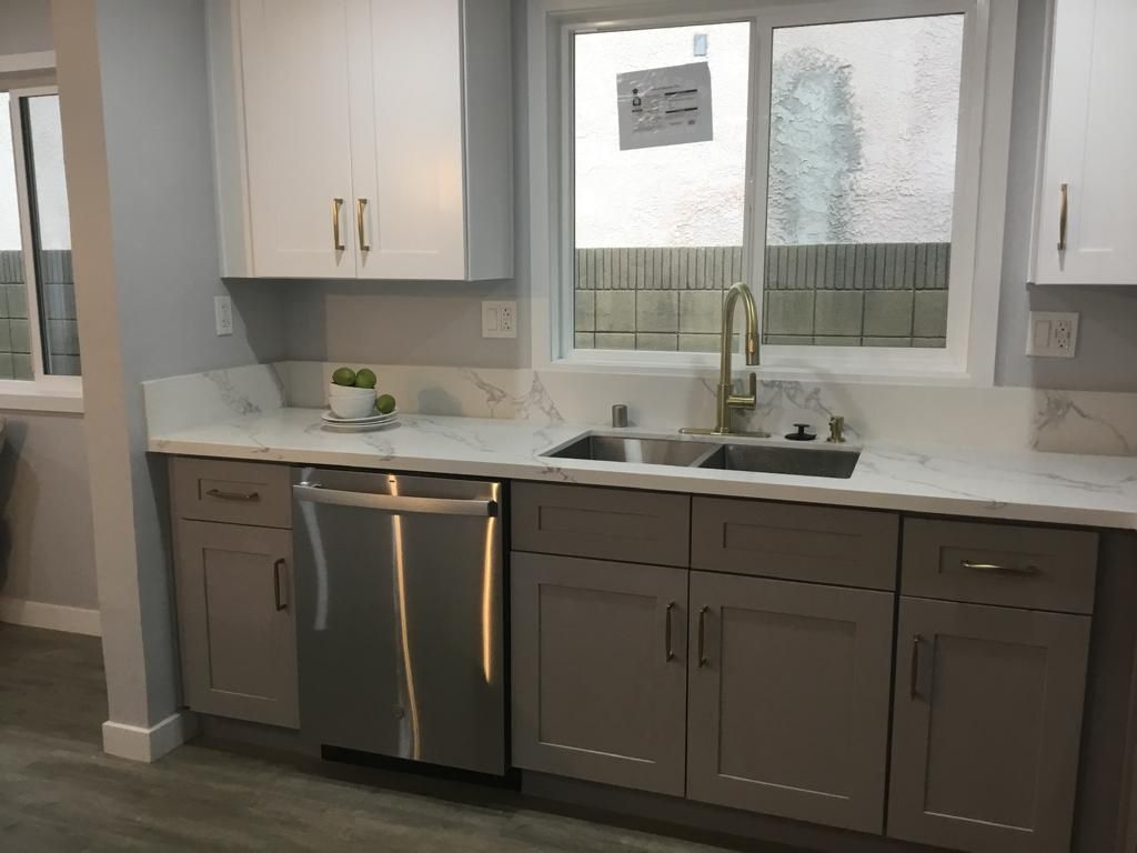 A kitchen with a sink a dishwasher and a window