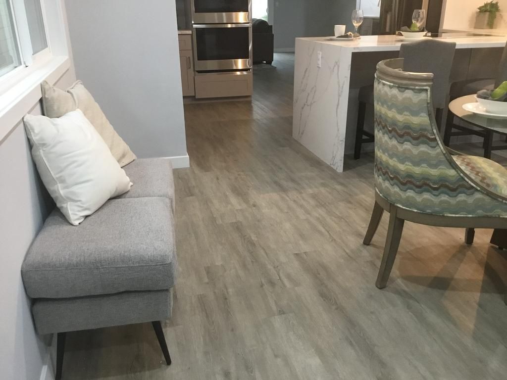 A living room with hardwood floors , a couch , chairs and a table.