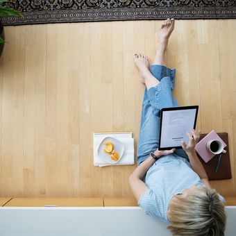 woman looking at electronic device while sitting on floor