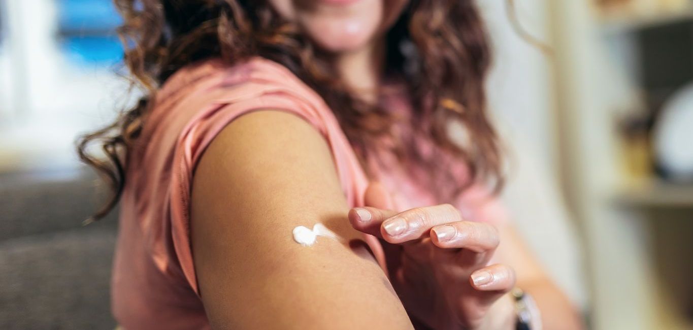 A woman is sitting on a couch getting a vaccine in her arm.