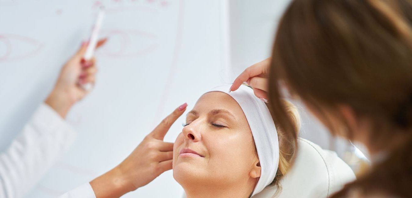A woman is getting her face examined by a doctor.