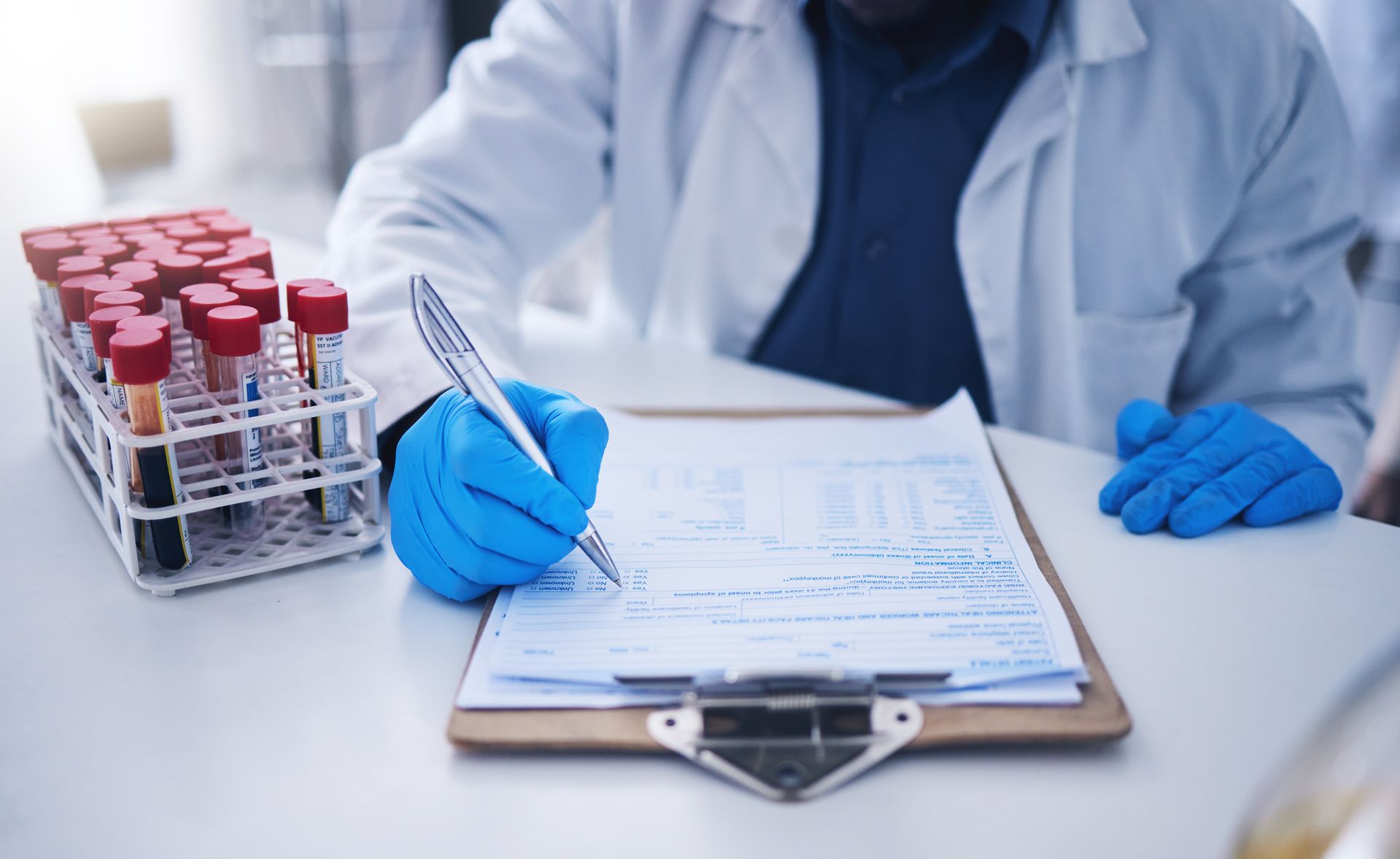 A scientist is writing on a clipboard in a laboratory.