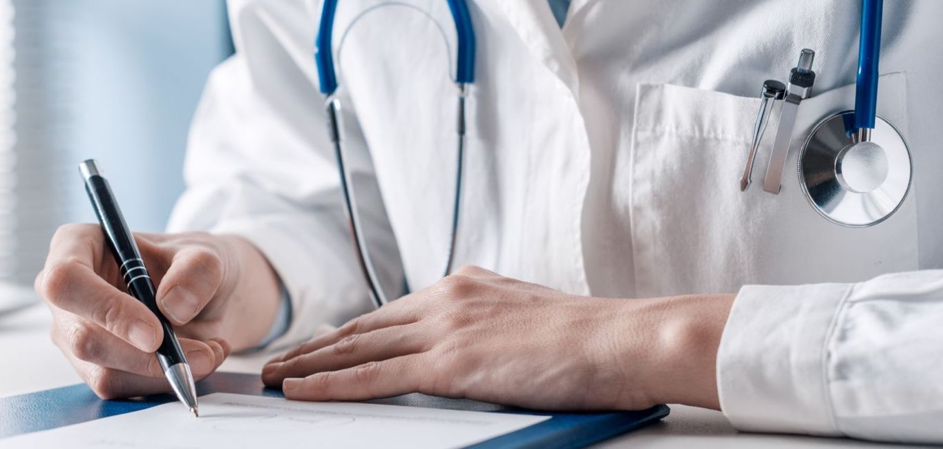 A doctor is writing on a piece of paper with a pen.