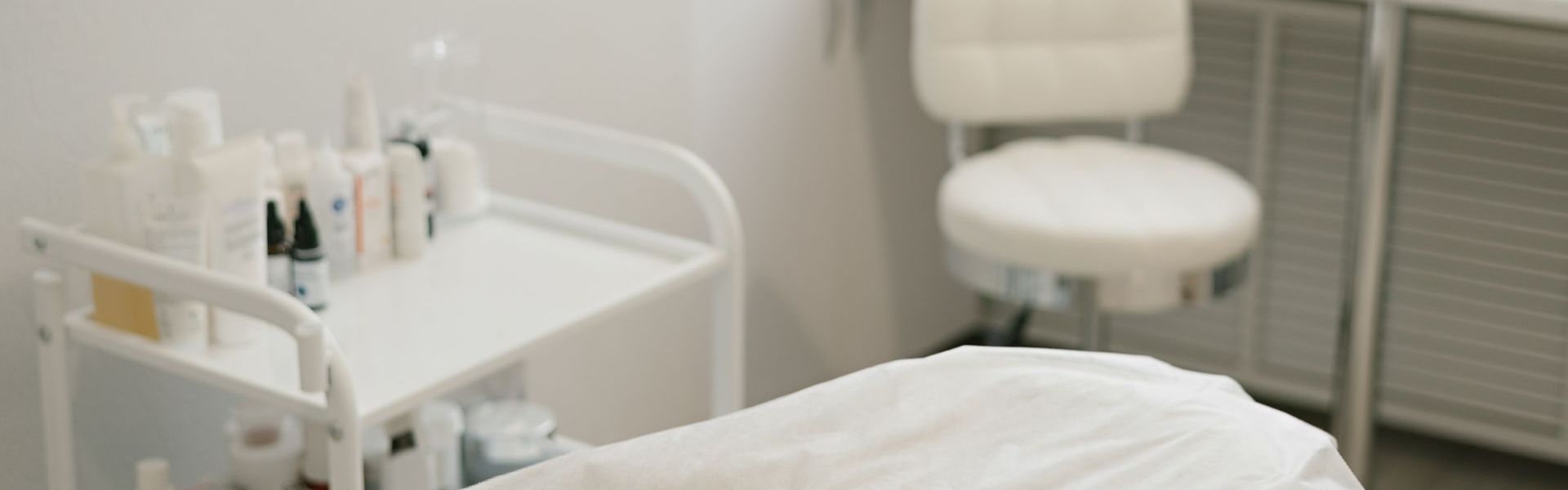 A white chair is sitting next to a bed in a room.