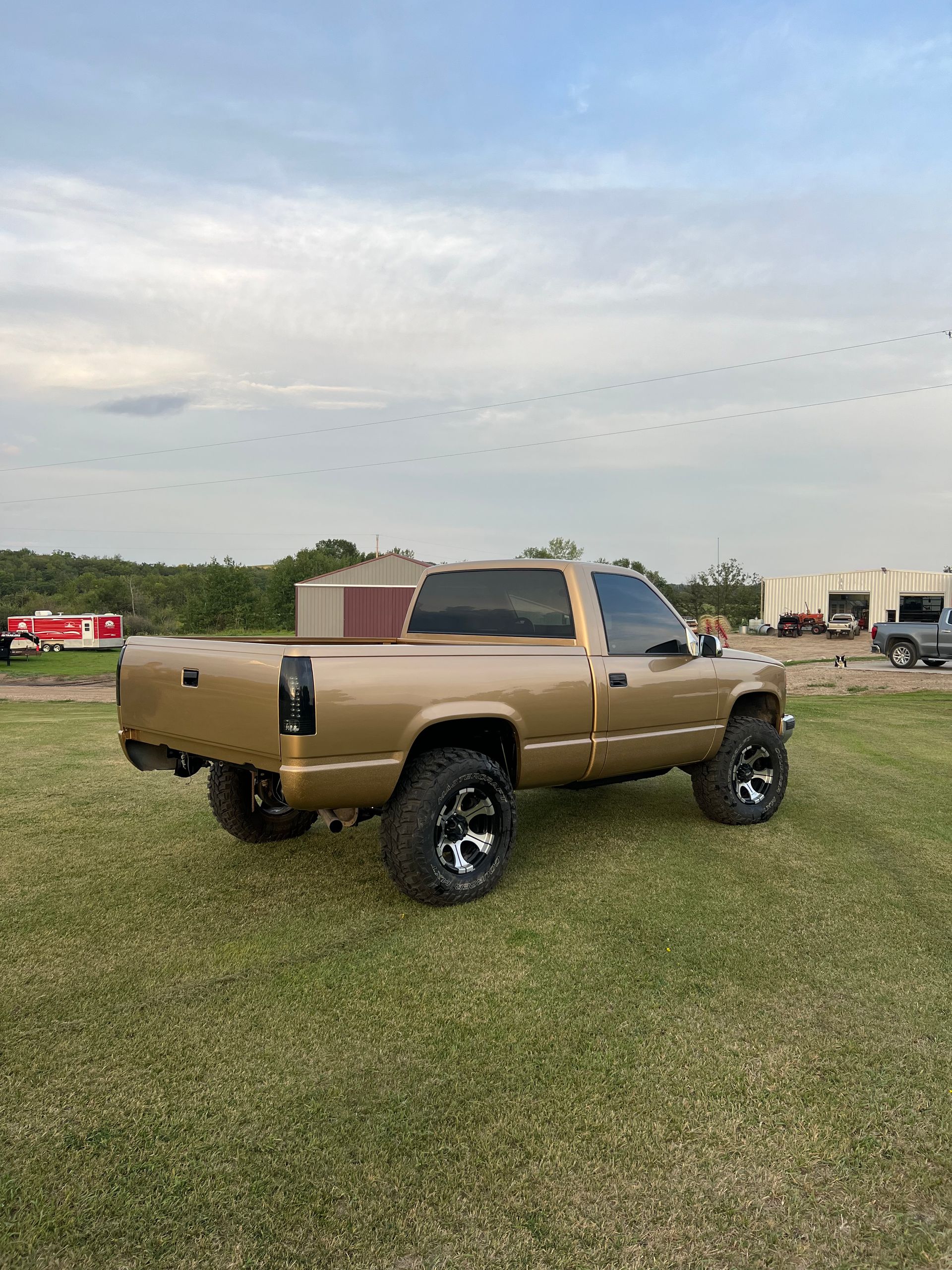 Tan pickup truck with black rims on grassy field.