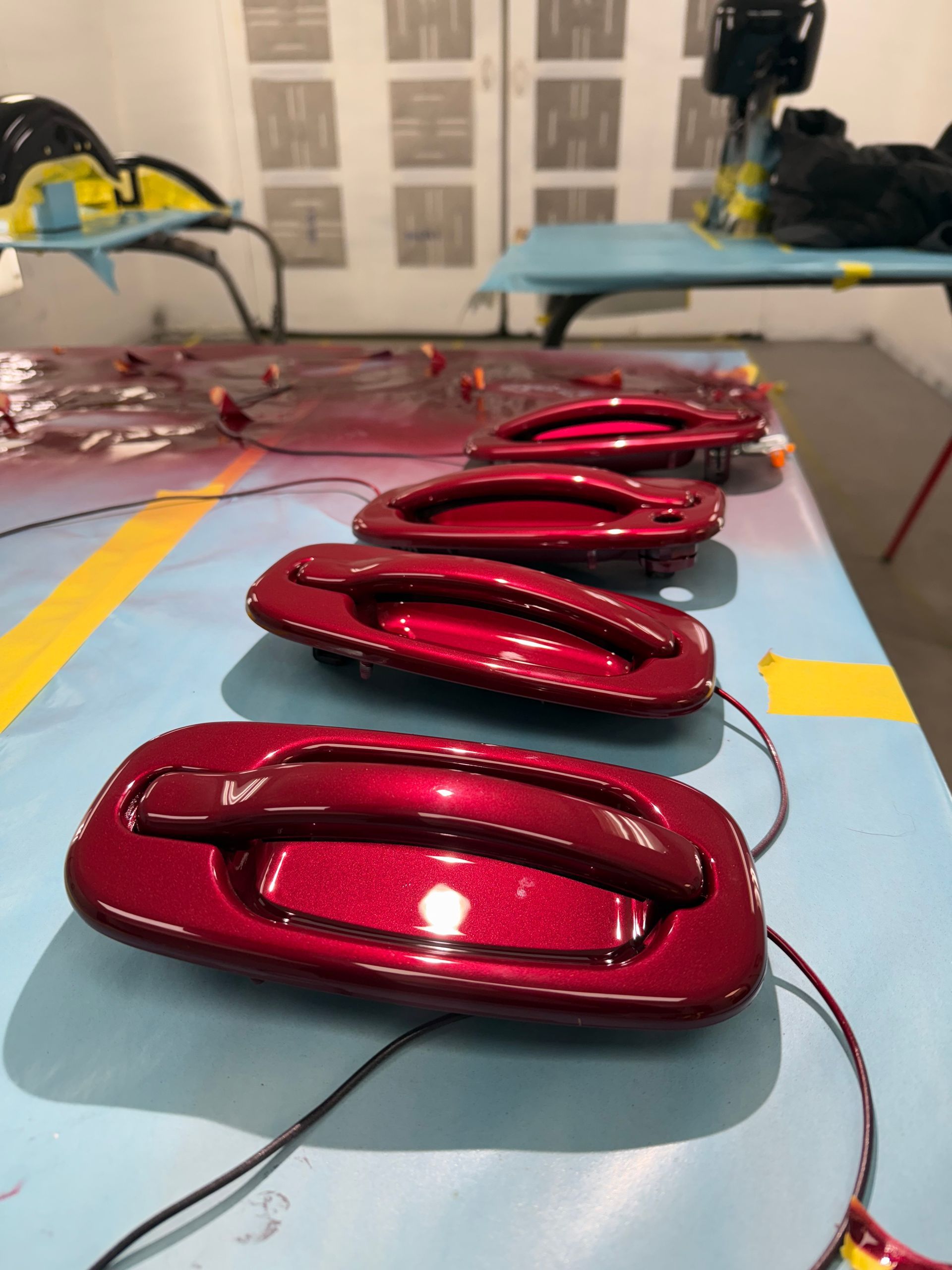 Red car door handles in a paint shop.