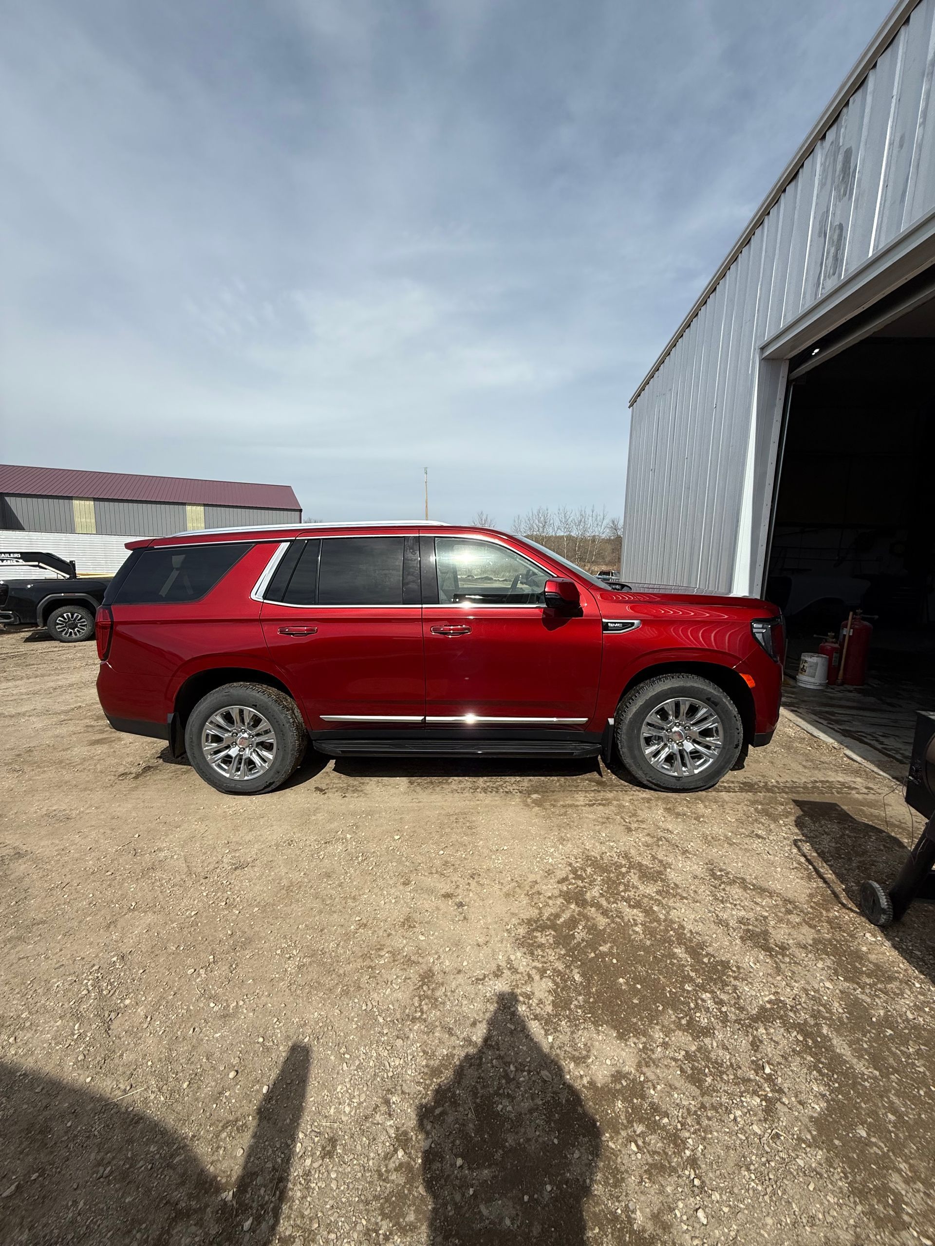 Red SUV parked outside a metallic building on a sunny day.