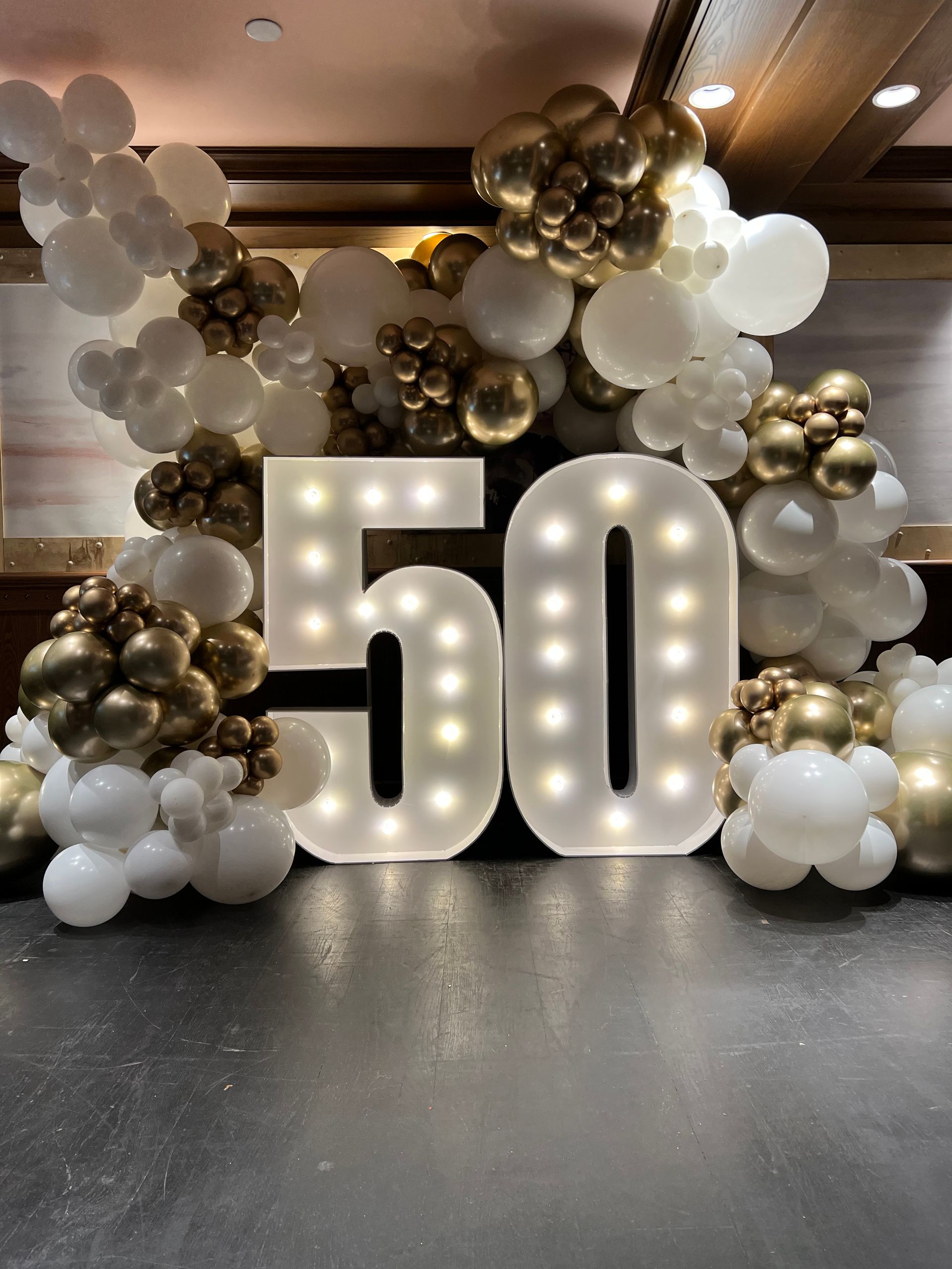 The number 50 is surrounded by balloons and lights.