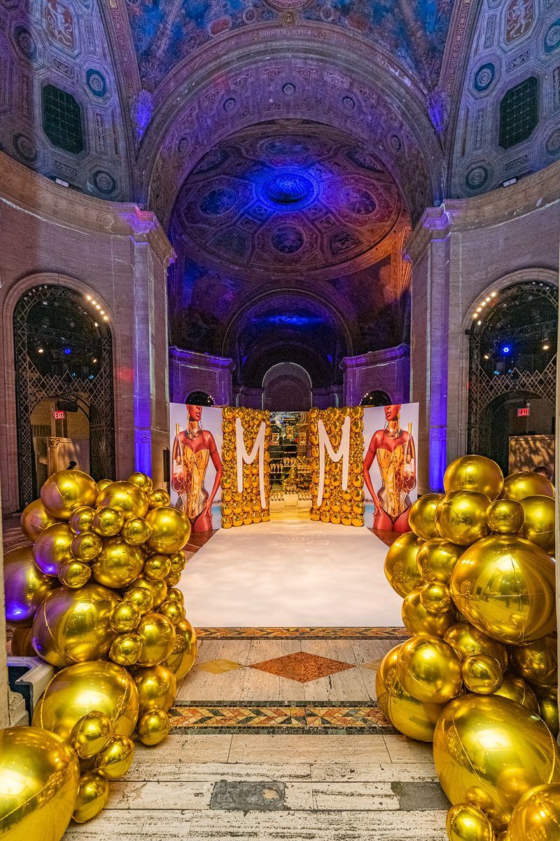 A bunch of gold balloons are sitting on the floor of a building.