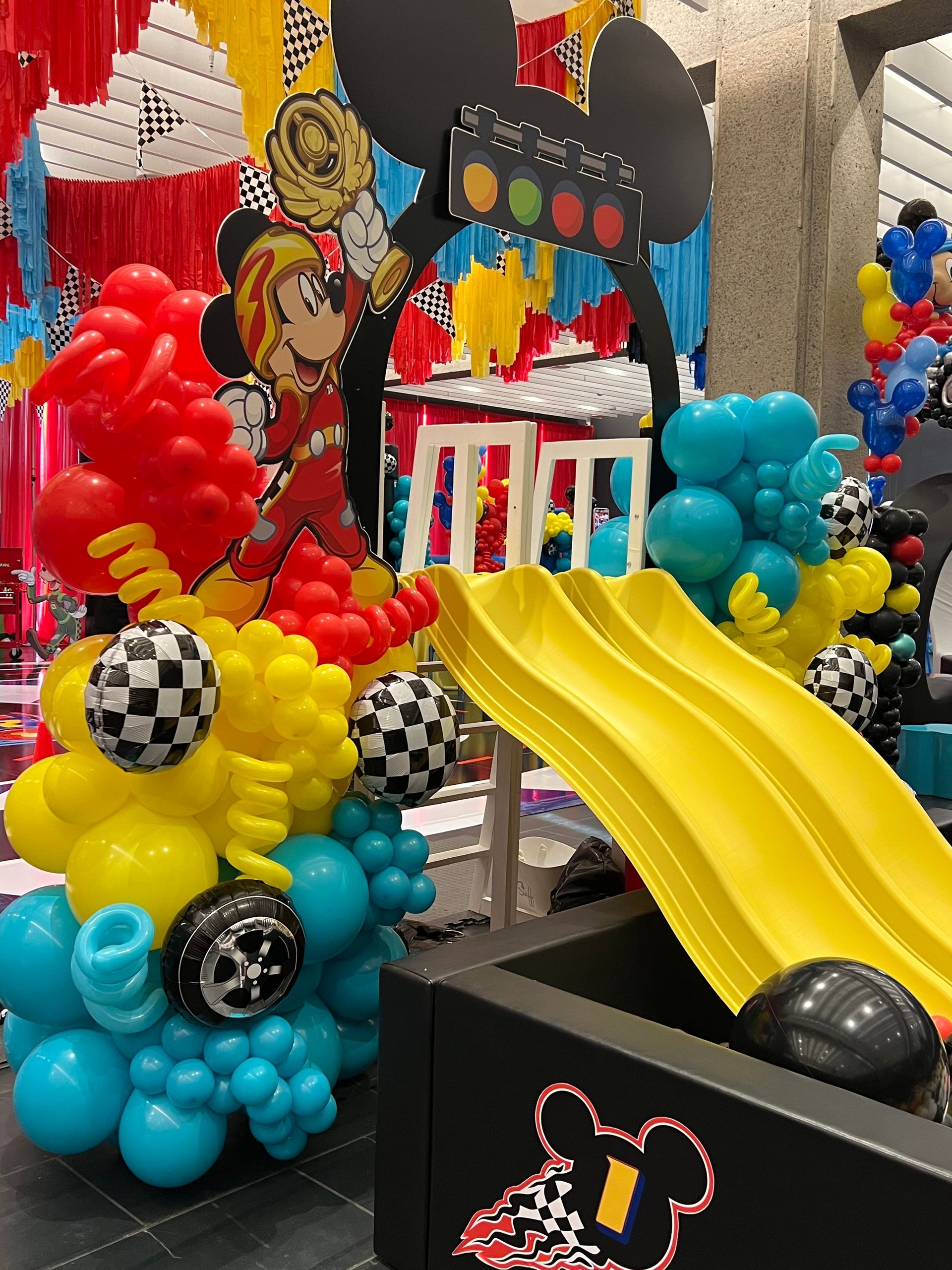 A mickey mouse themed birthday party with balloons and a slide.