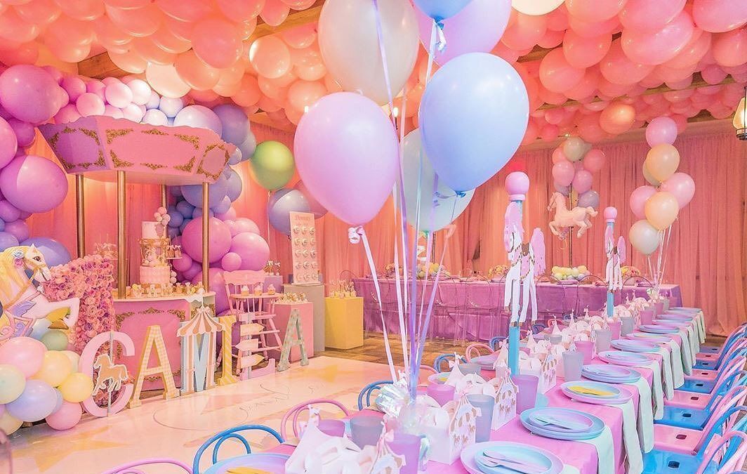 A room decorated with pink , purple , and blue balloons for a birthday party.
