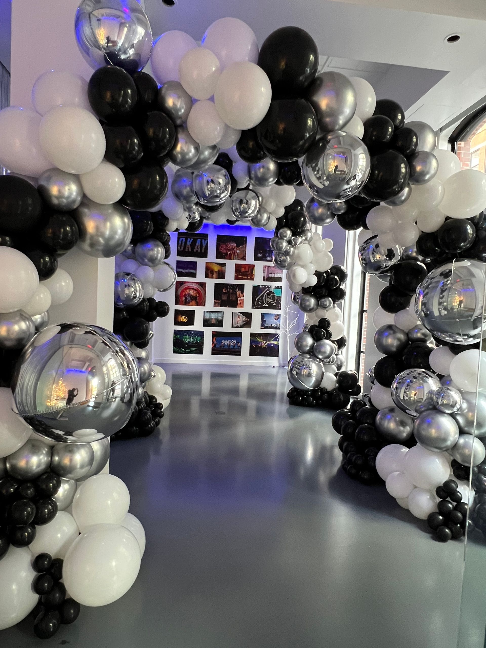 A room filled with black , white and silver balloons.