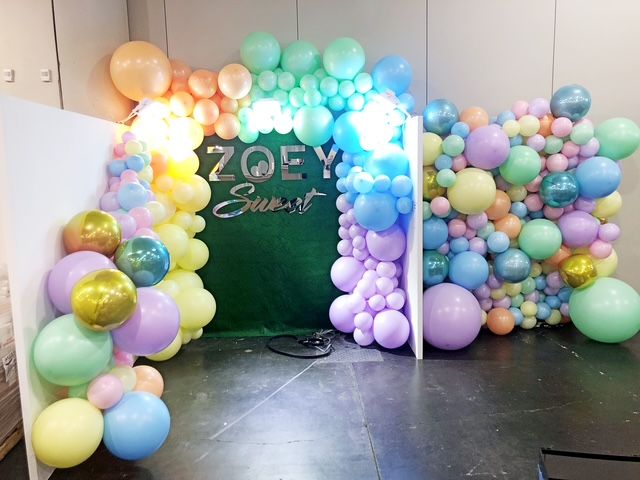 A fireplace decorated with silver balloons and flowers.