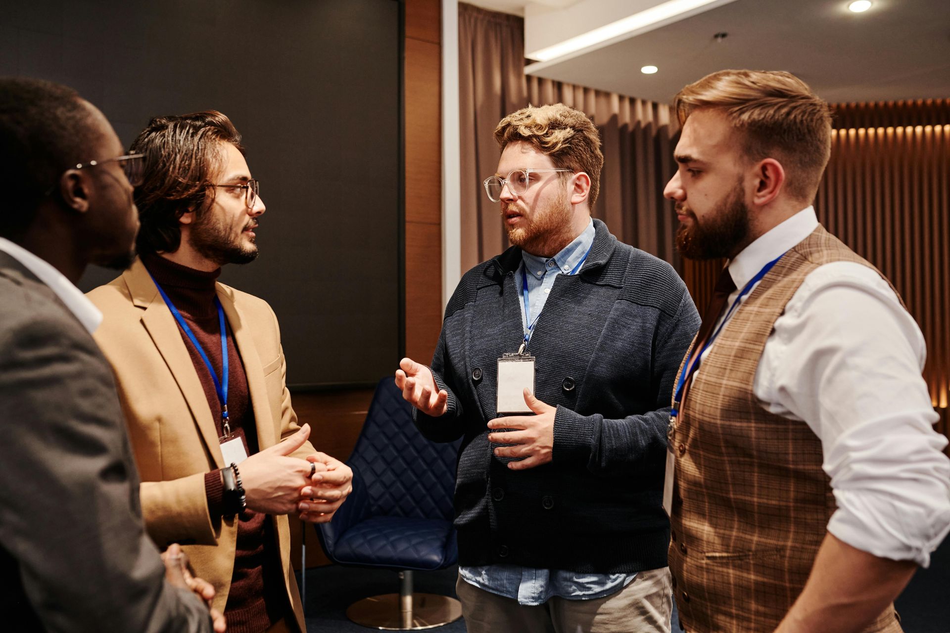 A group of men are standing around talking to each other in a room.