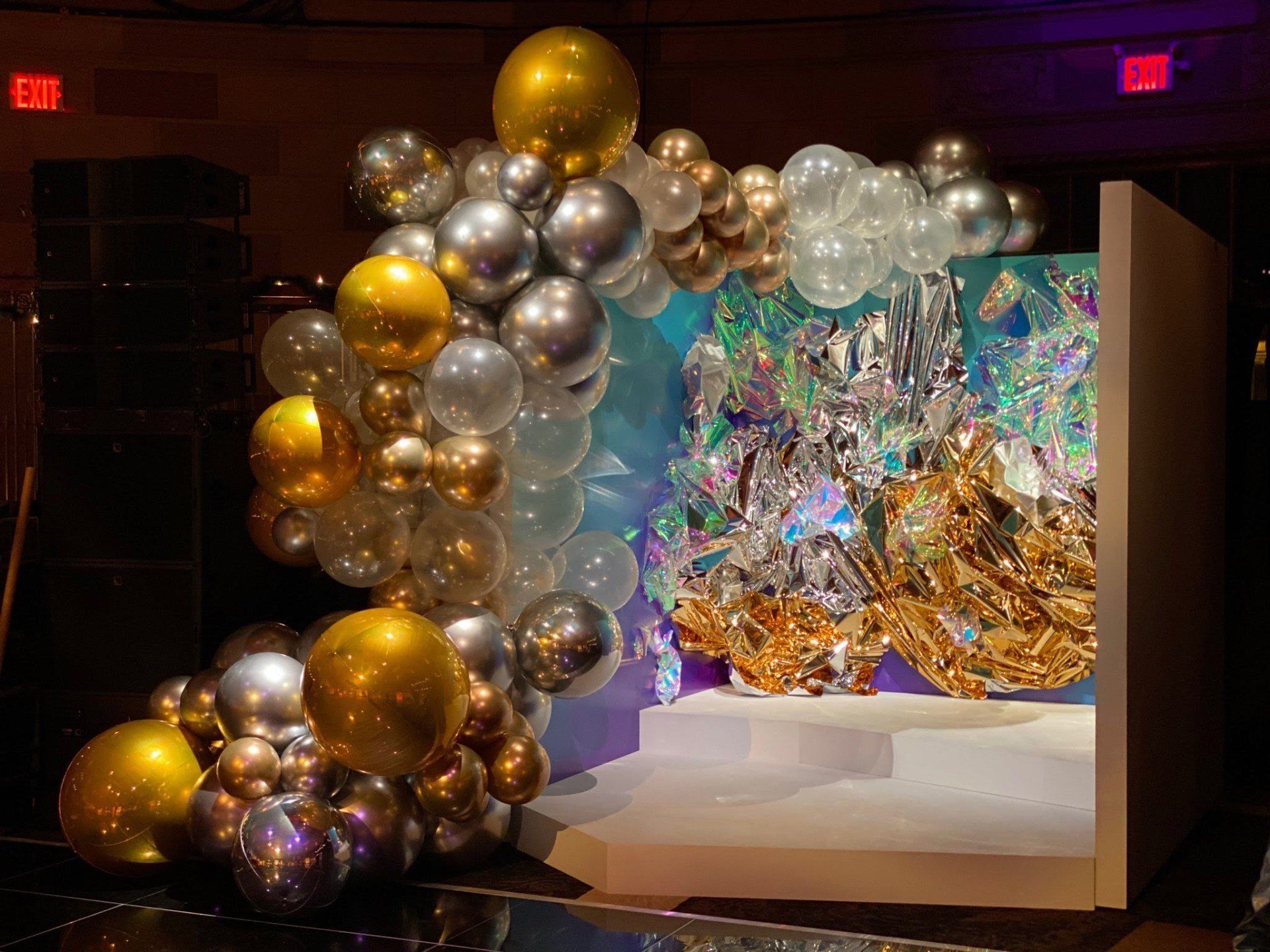A bunch of balloons are sitting on a stage in a room.
