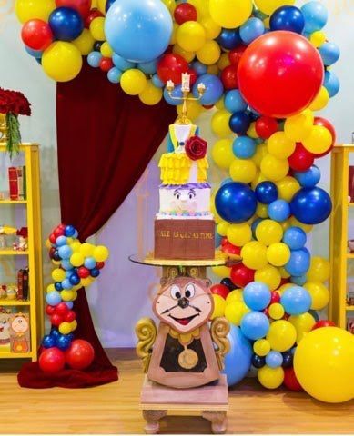 A room decorated with balloons and a cake on a table.