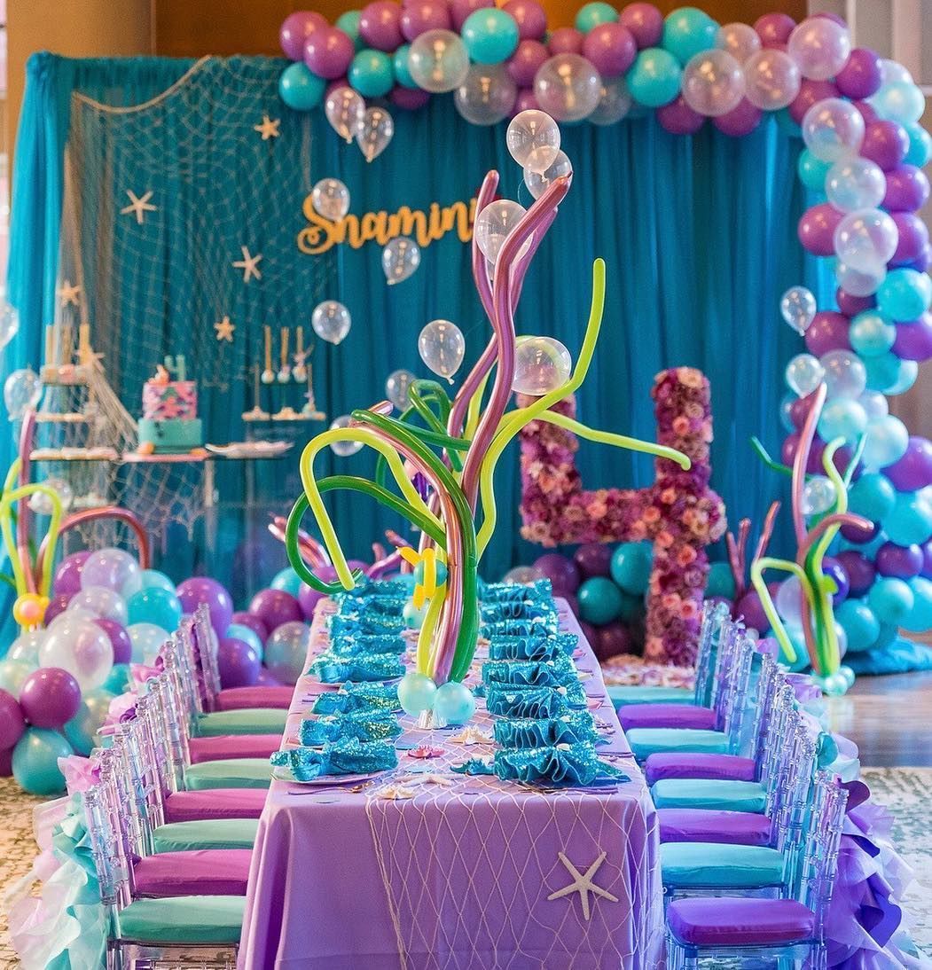 A table and chairs are decorated for a mermaid birthday party.