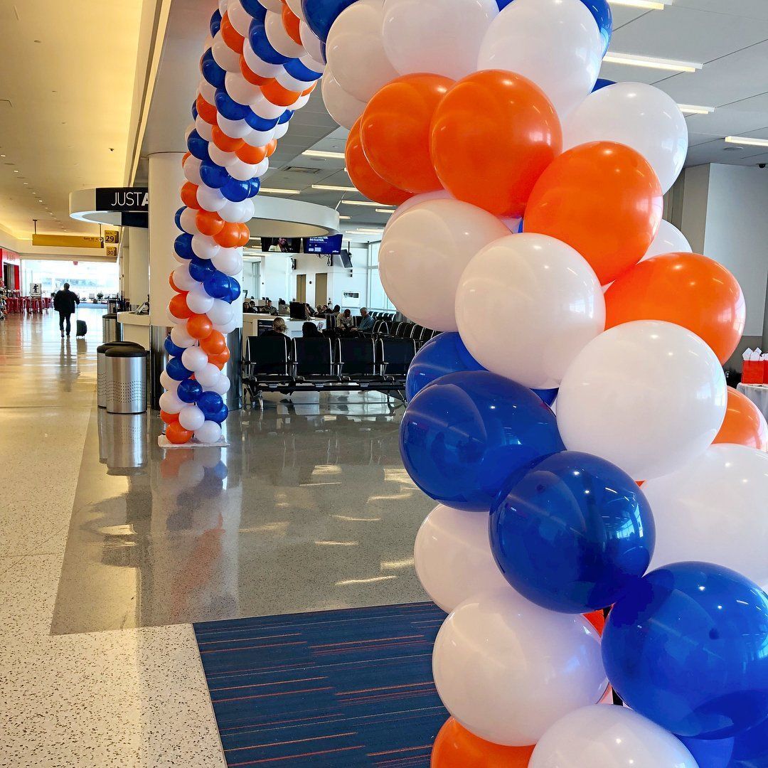 A bunch of blue white and orange balloons in an airport