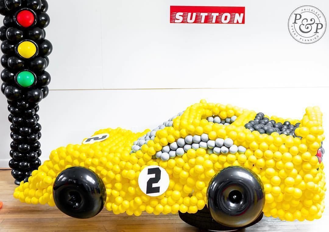 A yellow race car made out of balloons is sitting on a wooden table.