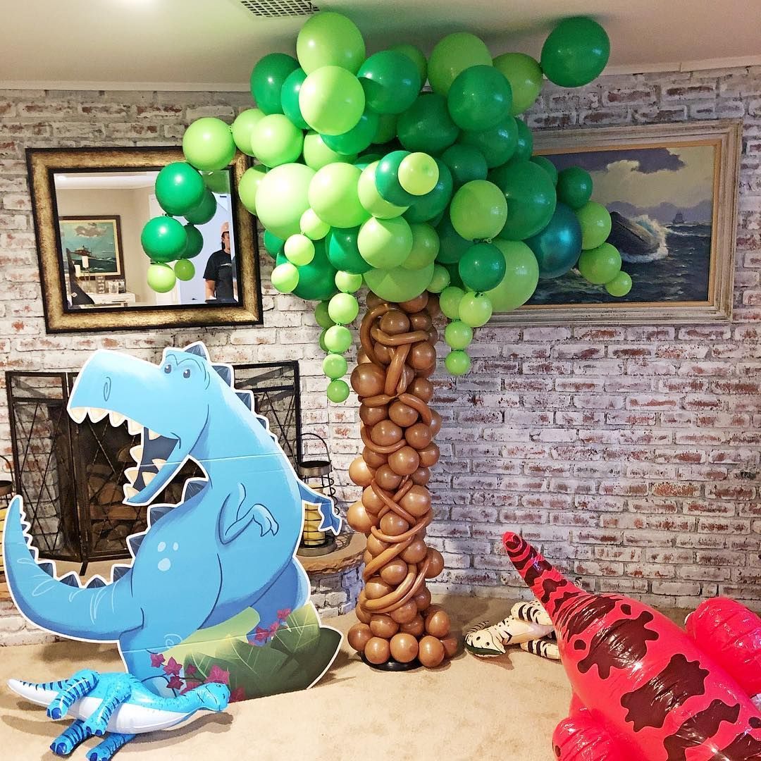 A room with a t-rex and a tree made of balloons