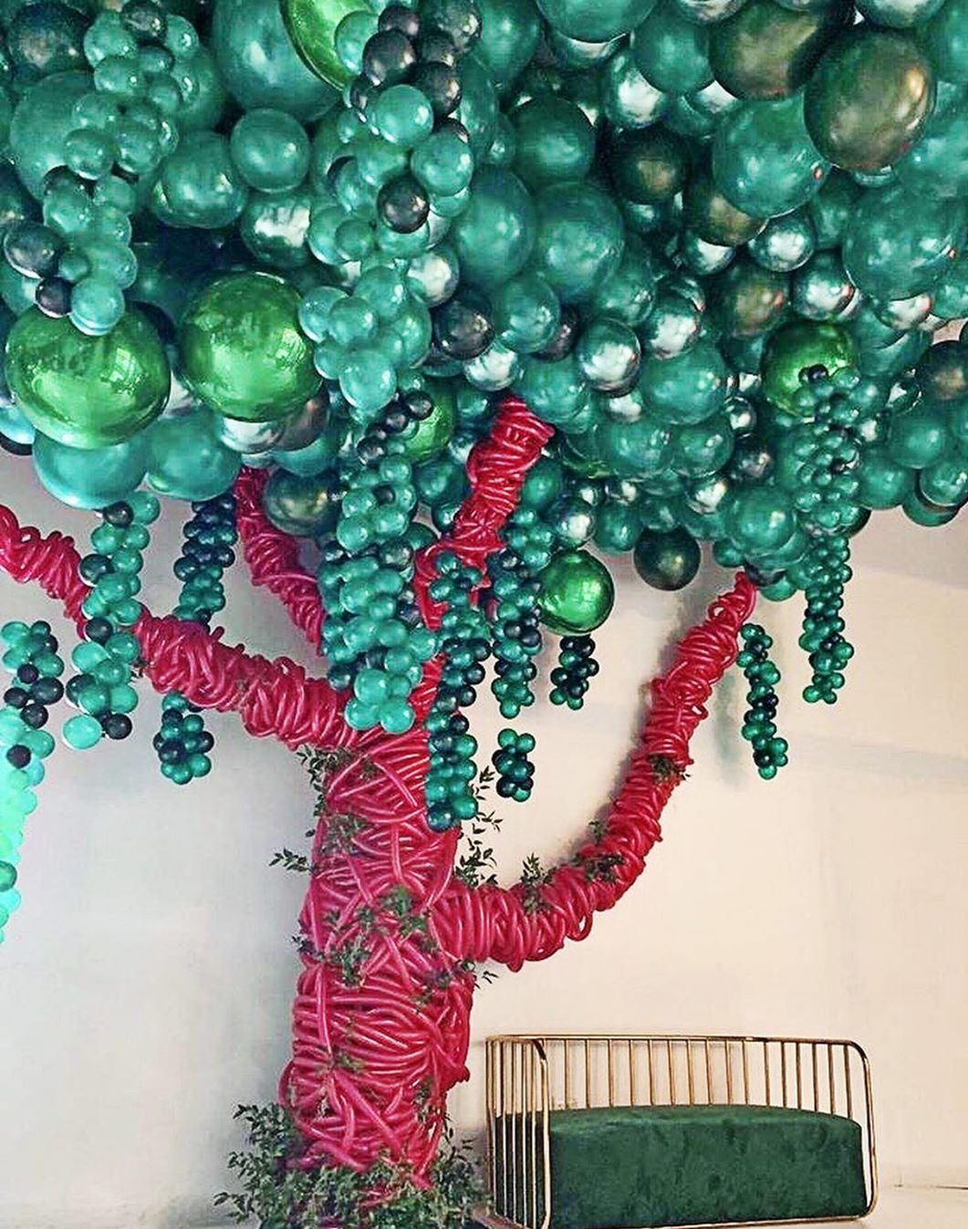 A tree made out of balloons is hanging from the ceiling.