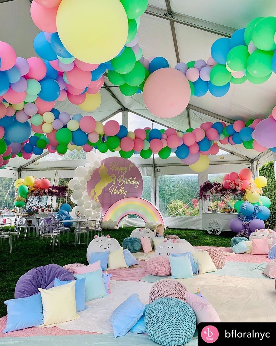A tent is decorated with balloons and pillows for a birthday party.