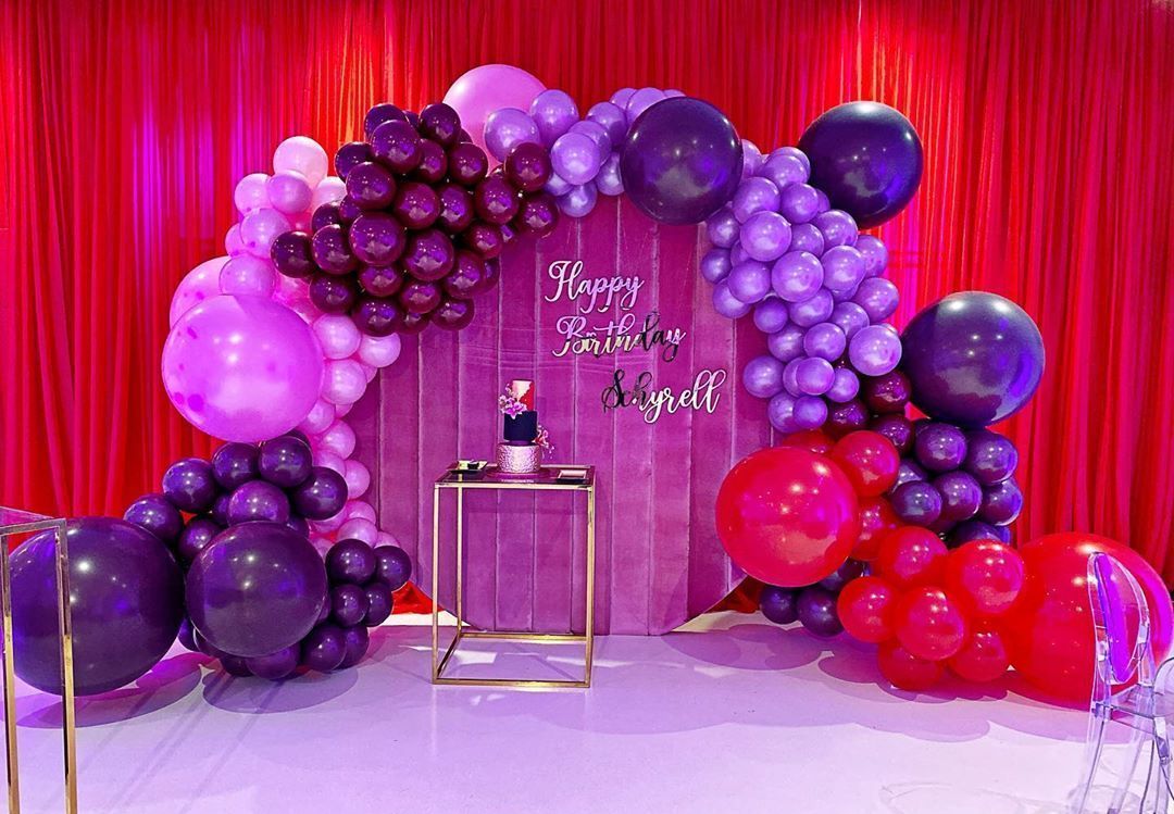 A room decorated with purple and red balloons for a birthday party.