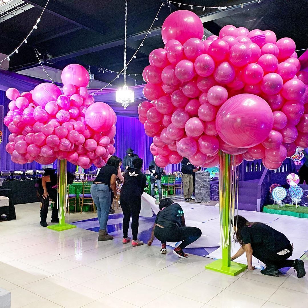 A bunch of pink balloons are sitting on top of each other in a room.