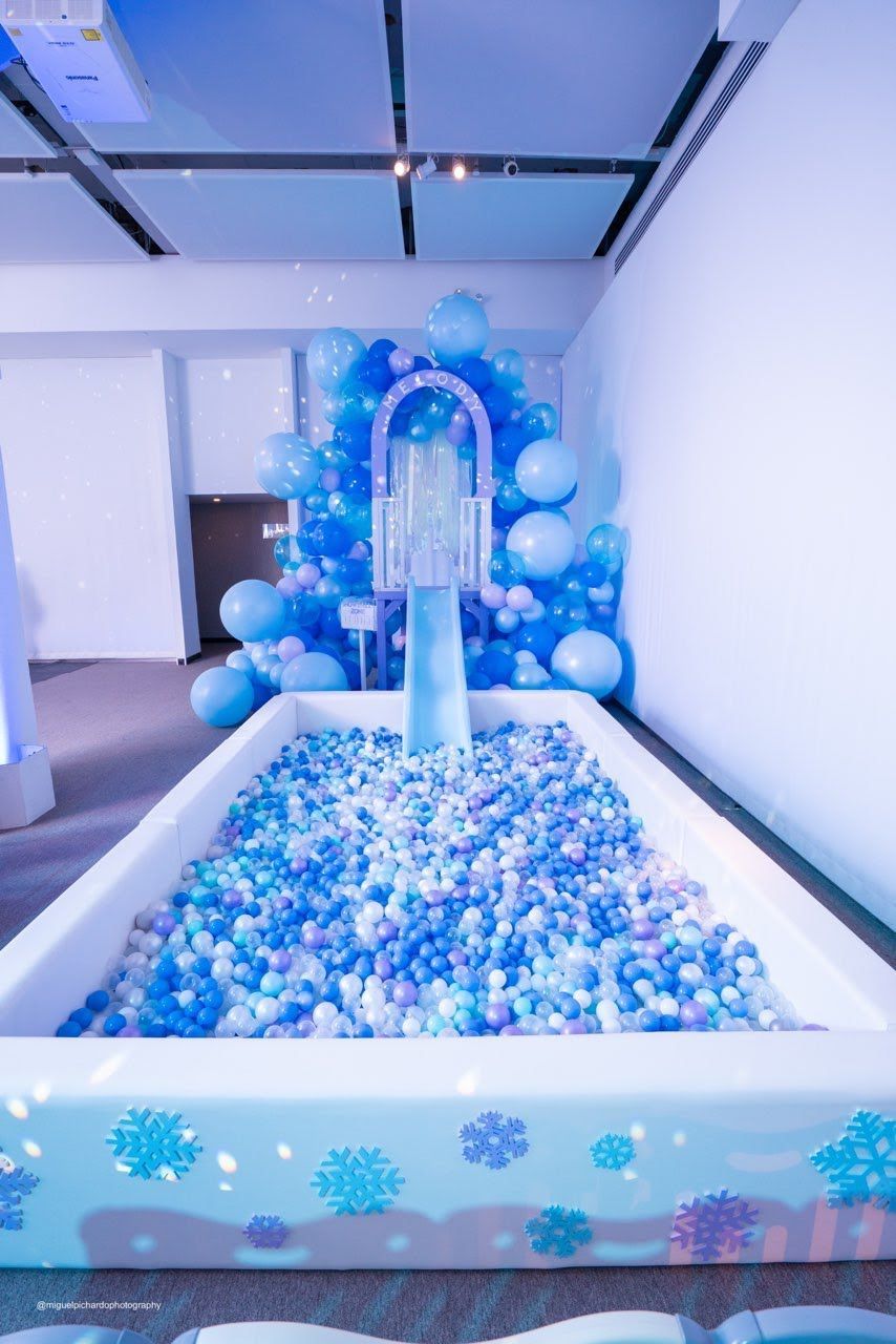 A large ball pit filled with blue and white balls in a room.