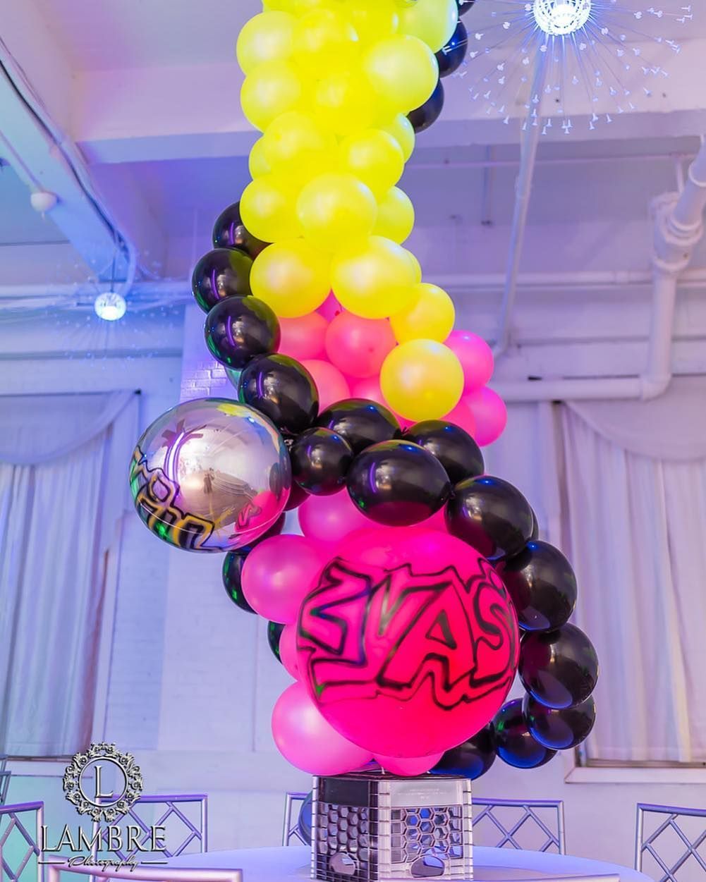 A bunch of balloons are hanging from the ceiling in a room.
