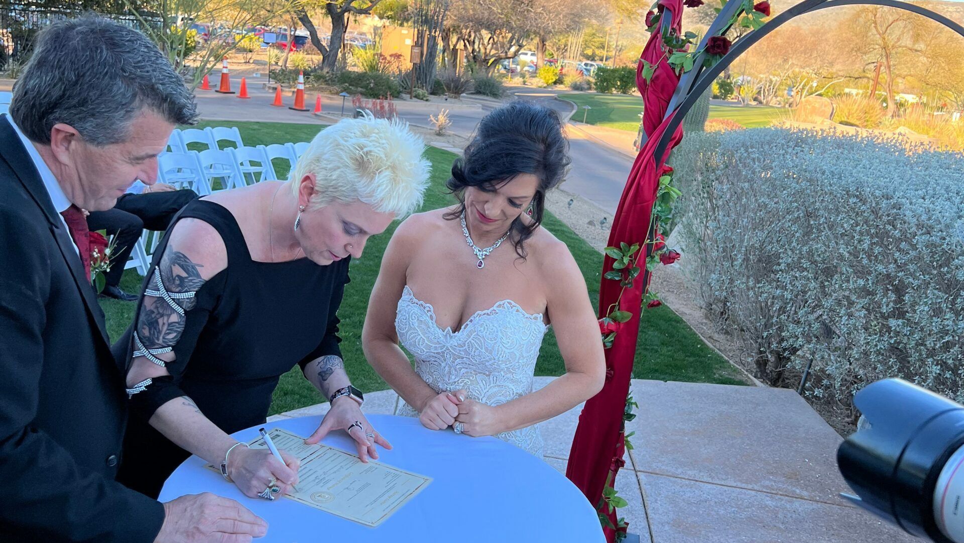 Julie and a bride sign marriage document