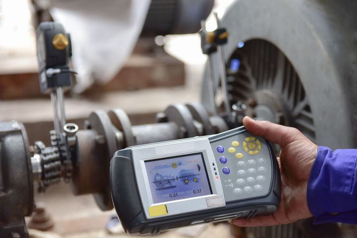 A person is holding a device in their hand in front of a fan.