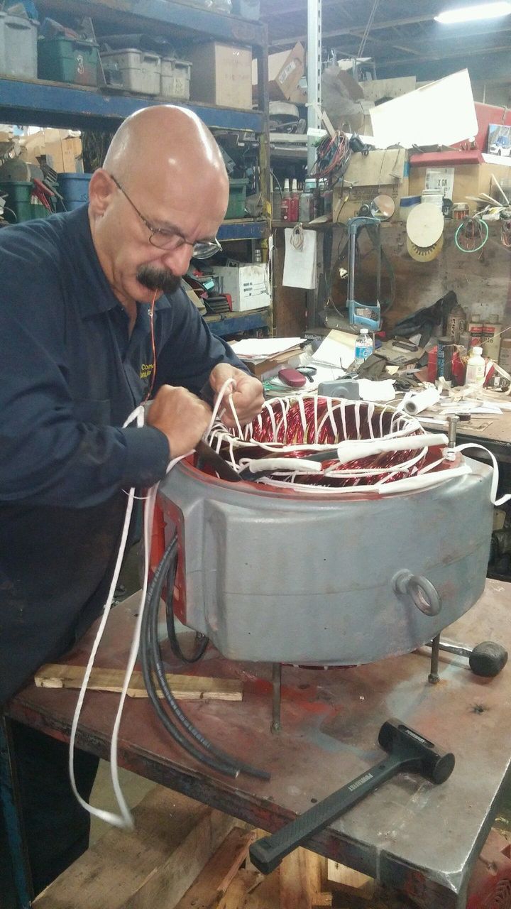 A man is working on an electric motor in a workshop.