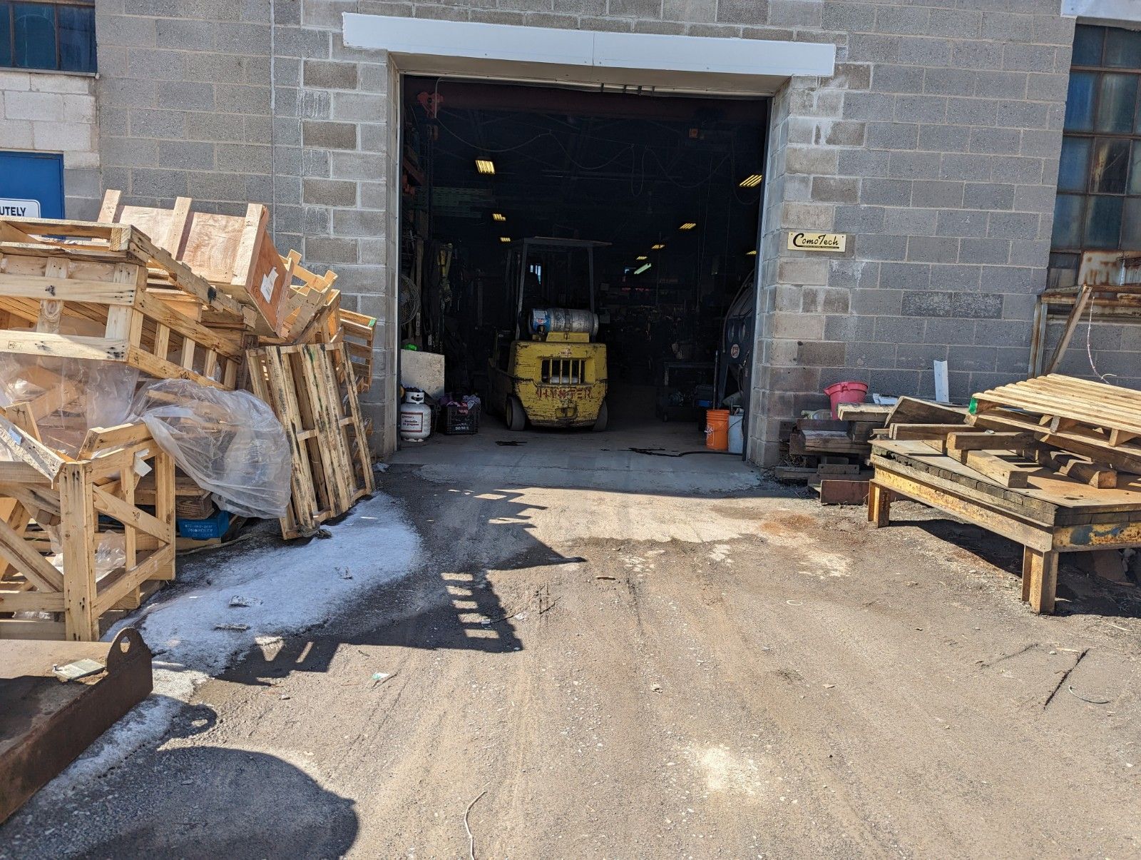 A yellow forklift is parked in front of a warehouse.