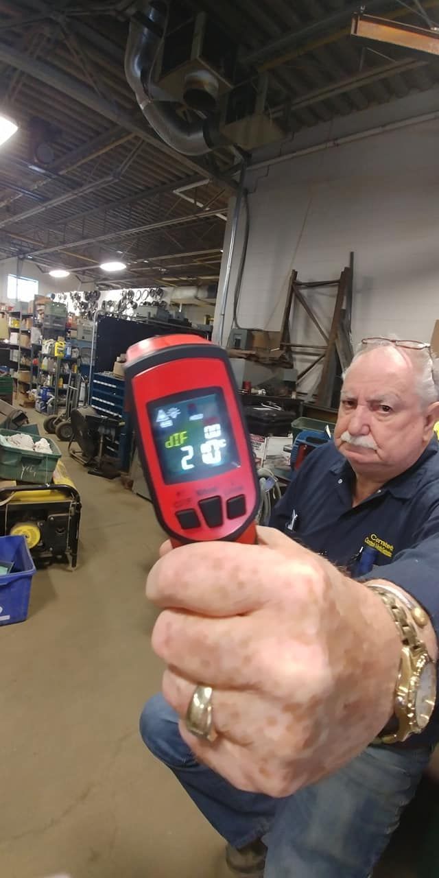 A man is holding a thermometer in his hand in a warehouse.