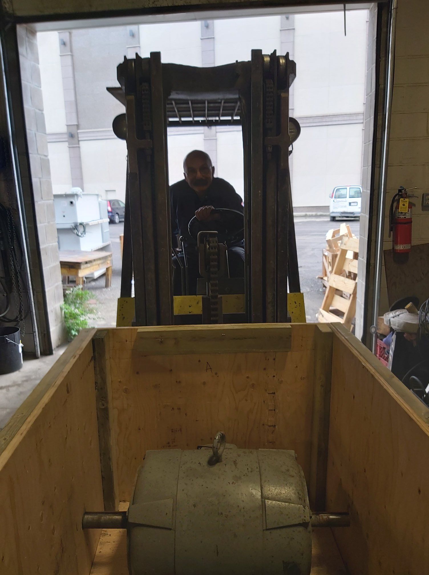 A man is driving a forklift in a wooden box