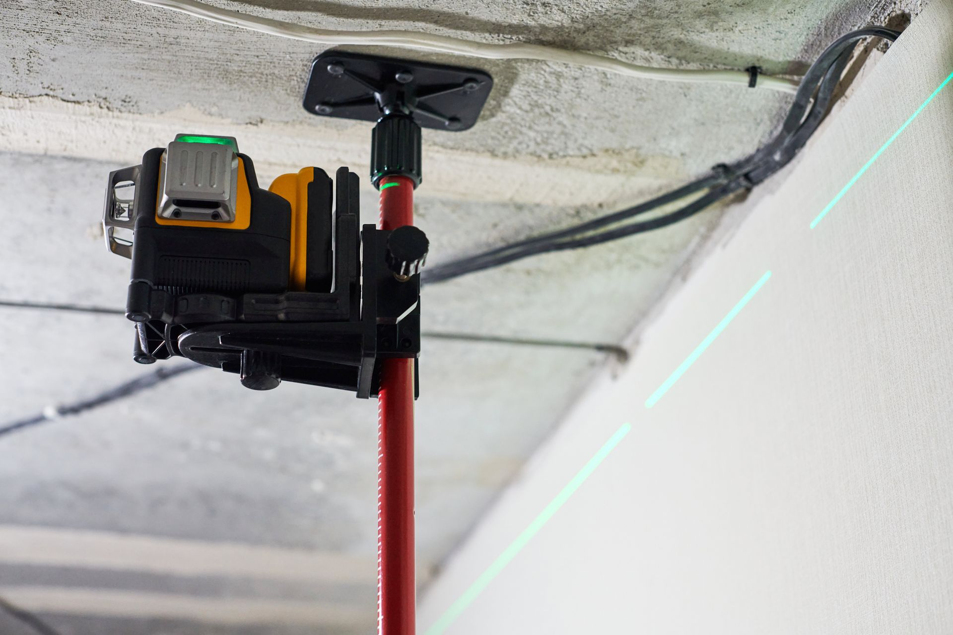 A green laser level is sitting on top of a red pole.