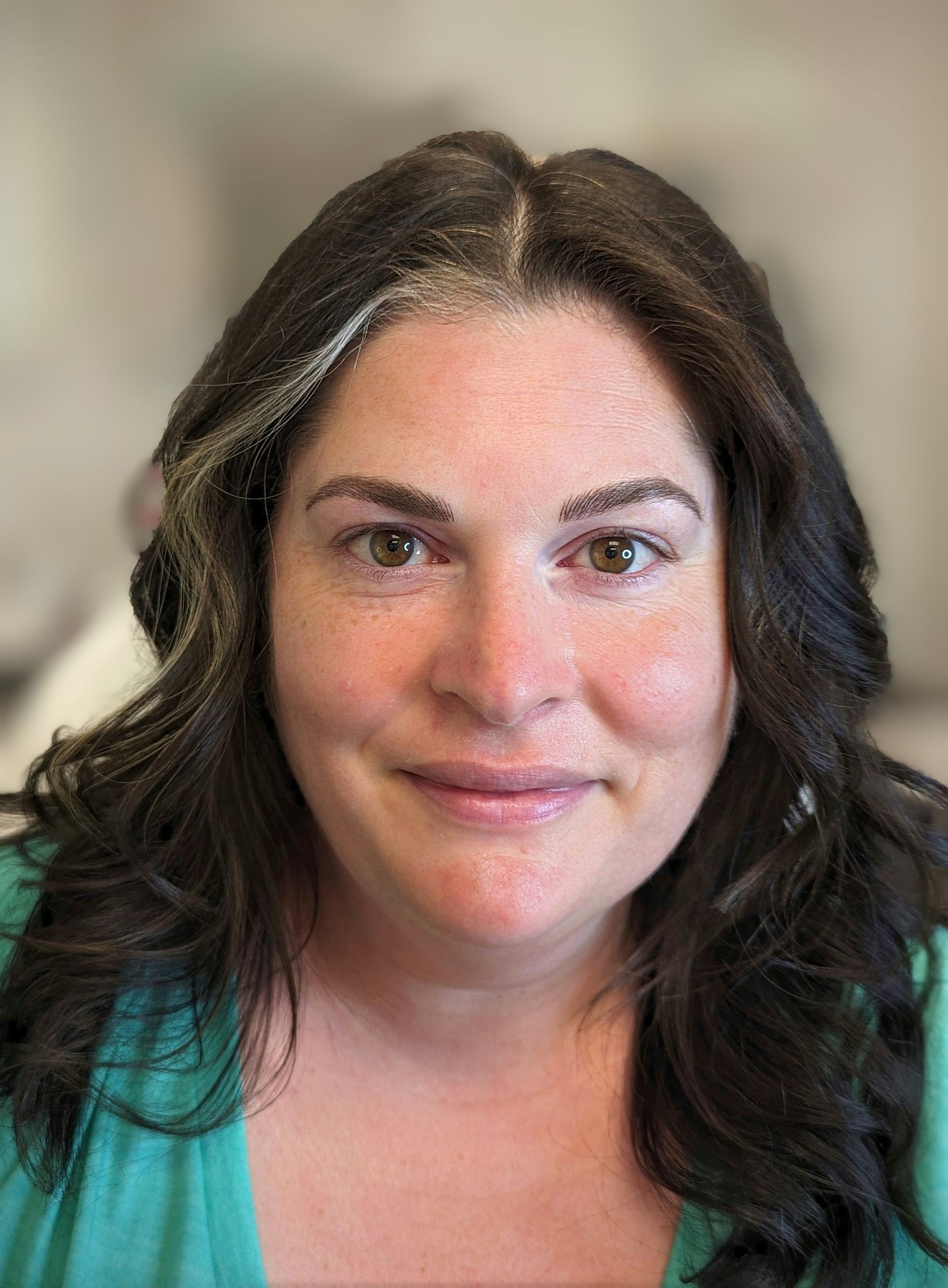 A close up of a woman 's face with long hair and a green shirt.